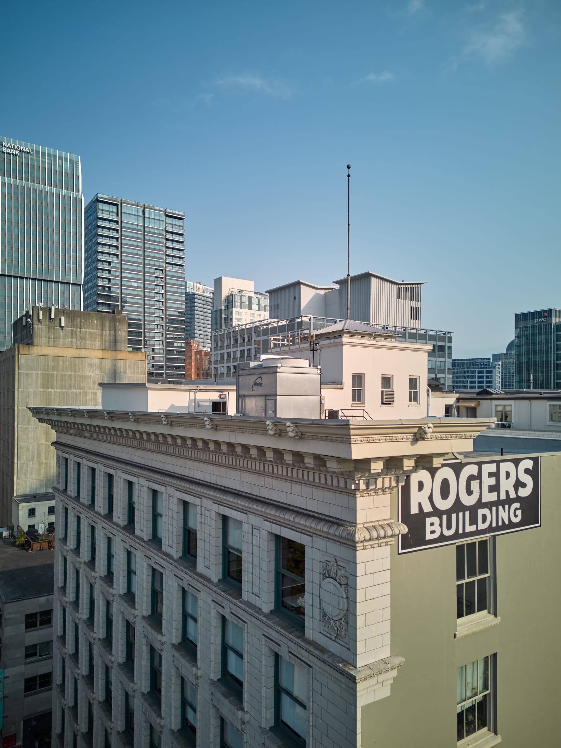 The Rogers Building's terracotta cornice and painted rooftop sign against Vancouver's modern towers